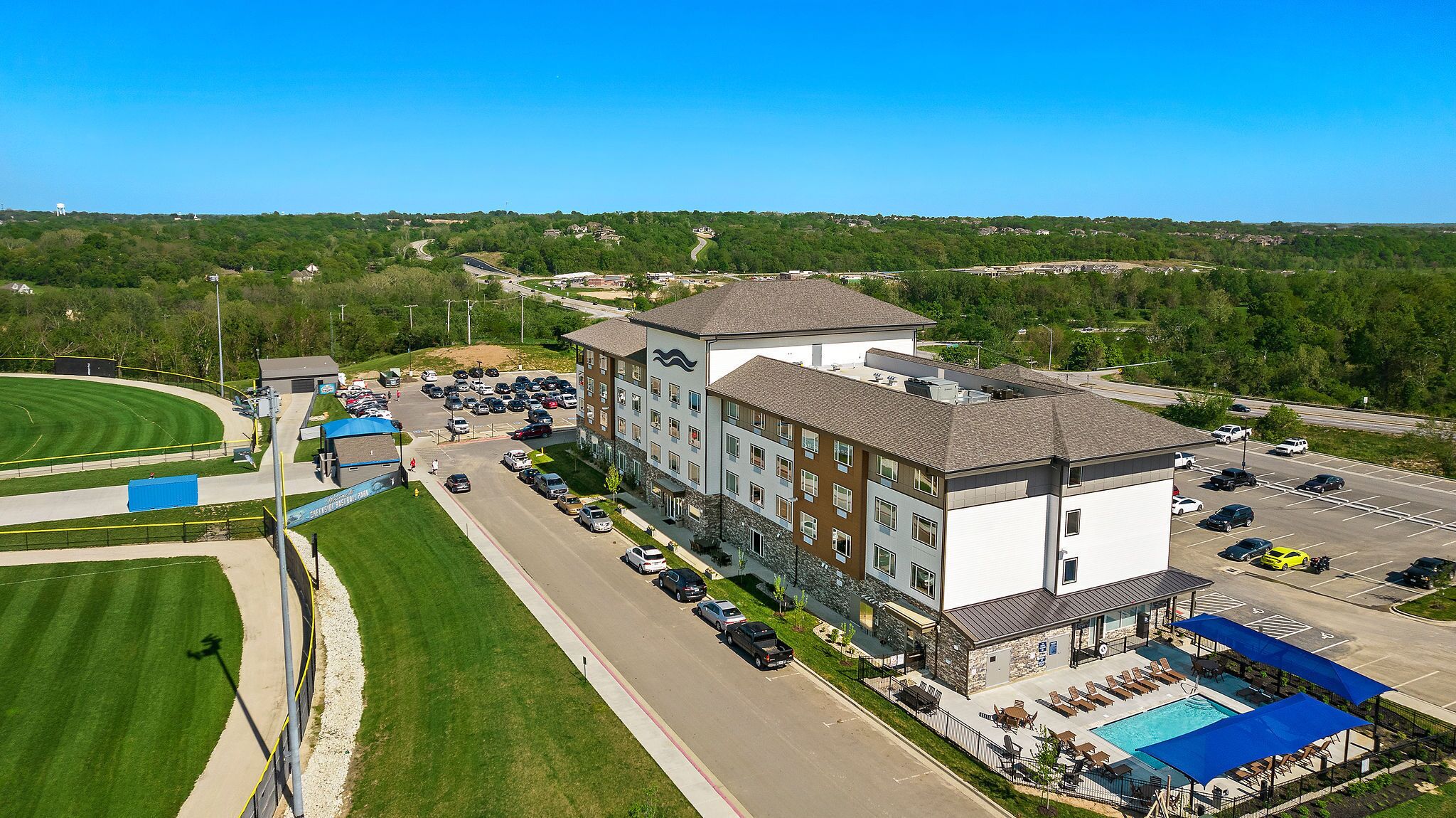 A multi-story hotel with a swimming pool and a parking lot.
