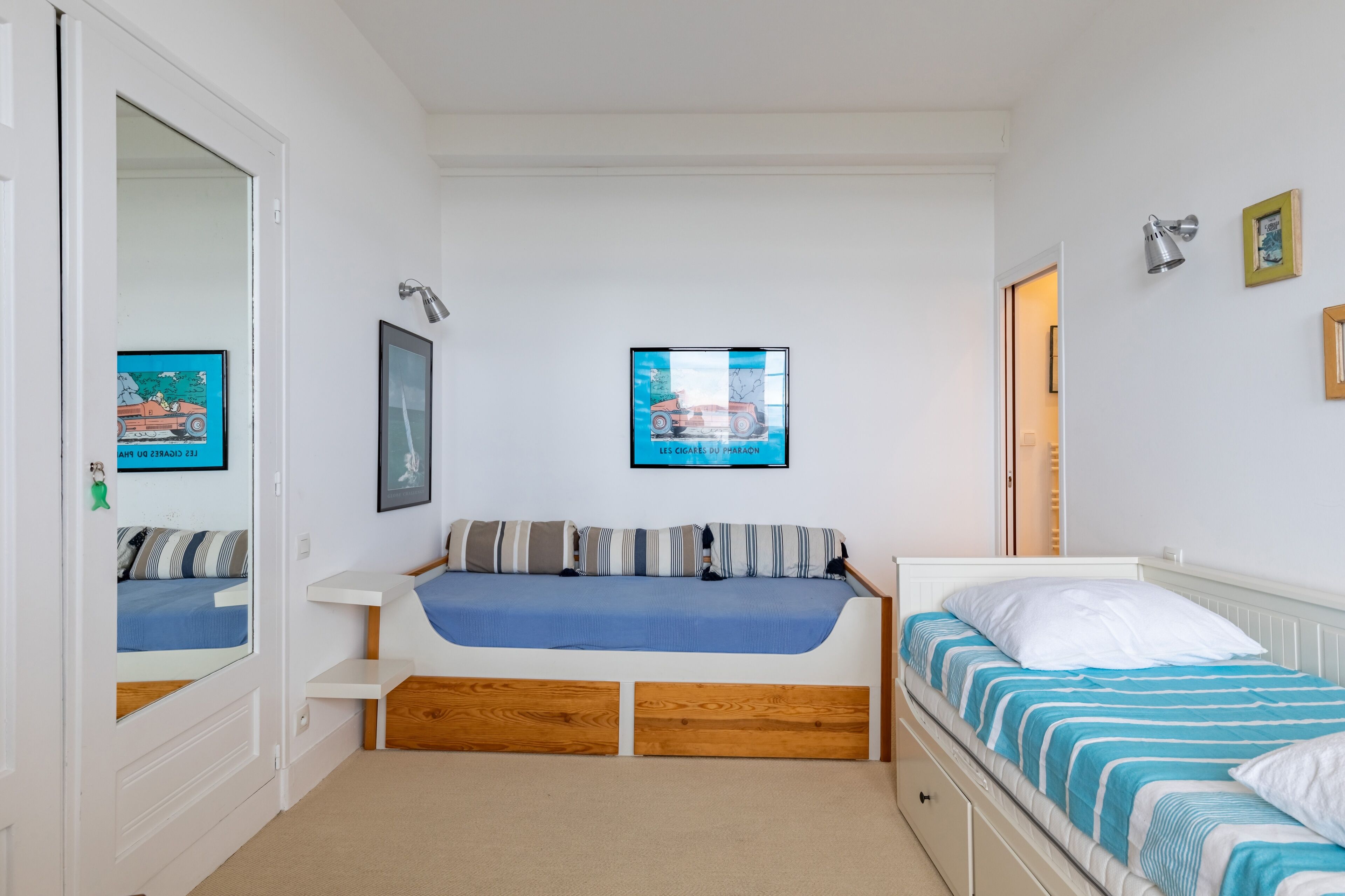 Een slaapkamer met een bed, een bijzetbed, een bureau en een kledingkast.