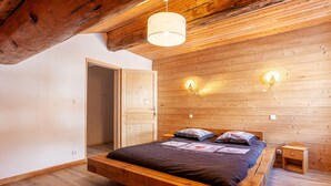 A wooden-paneled bedroom with a bed, a nightstand, and two wall-mounted lights. - LA RECHASSE - Proche des pistes (Termignon)