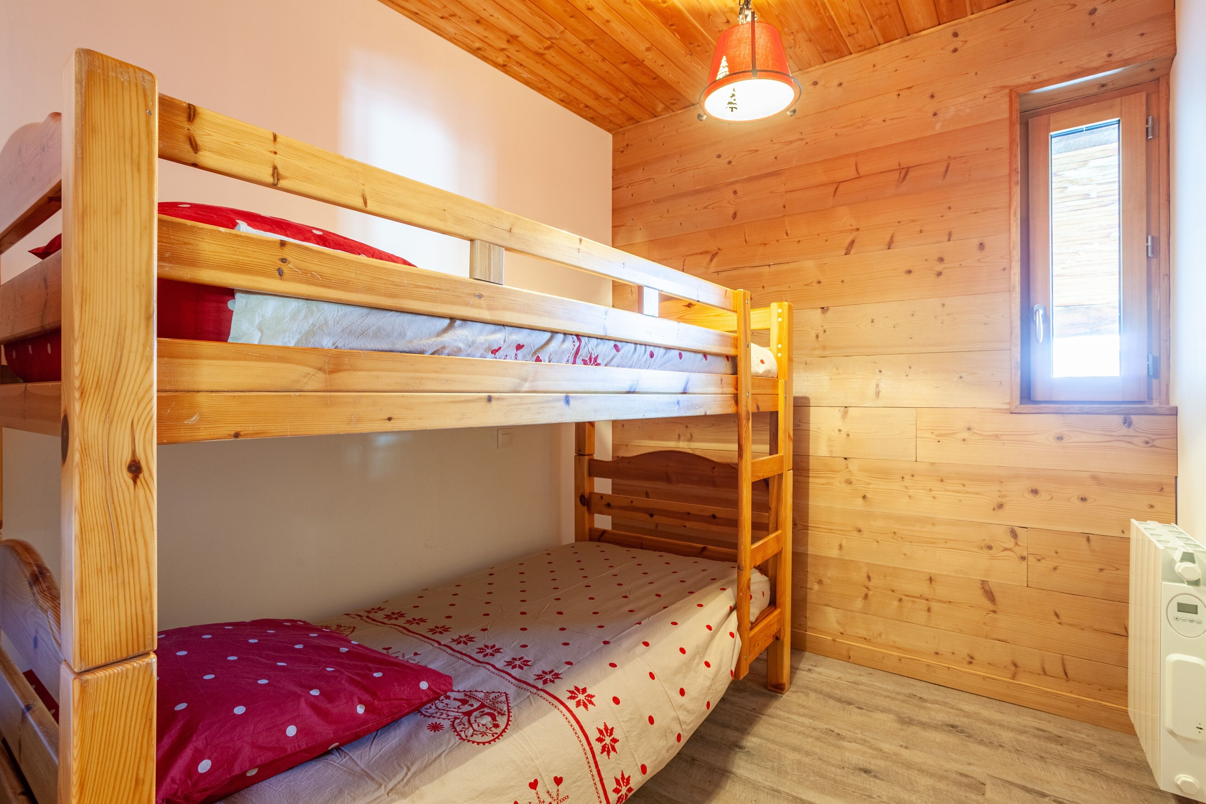 A bunk bed room with wooden walls and a window.