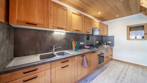 A modern kitchen with wooden cabinets, a granite countertop, and a built-in oven. - LA RECHASSE - Proche des pistes (Termignon)