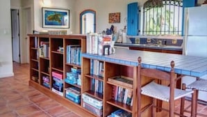 A library with bookshelves, a reading area, and a window with a view. - San Costanzo 2 br/ba Delightful breezes, Caribbean views, hot tub and generator! (St.John)