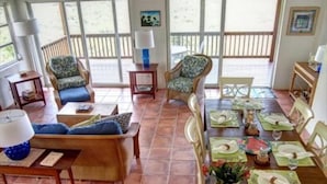 A dining area with a wooden table set for a meal, surrounded by wicker chairs and a sofa. - San Costanzo 2 br/ba Delightful breezes, Caribbean views, hot tub and generator! (St.John)