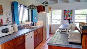A kitchen with wooden cabinets, a dishwasher, a microwave, and a sink. - San Costanzo 2 br/ba Delightful breezes, Caribbean views, hot tub and generator! (St.John)