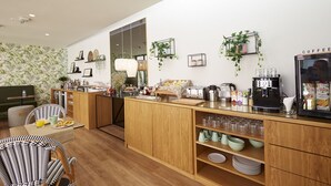 A modern kitchen with wooden cabinets, a coffee machine, and various kitchen appliances. There is a dining area with a table and chairs, and a counter with a coffee machine and a refrigerator. - Sintra Green Chalet - Bed & Breakfast (Sintra)