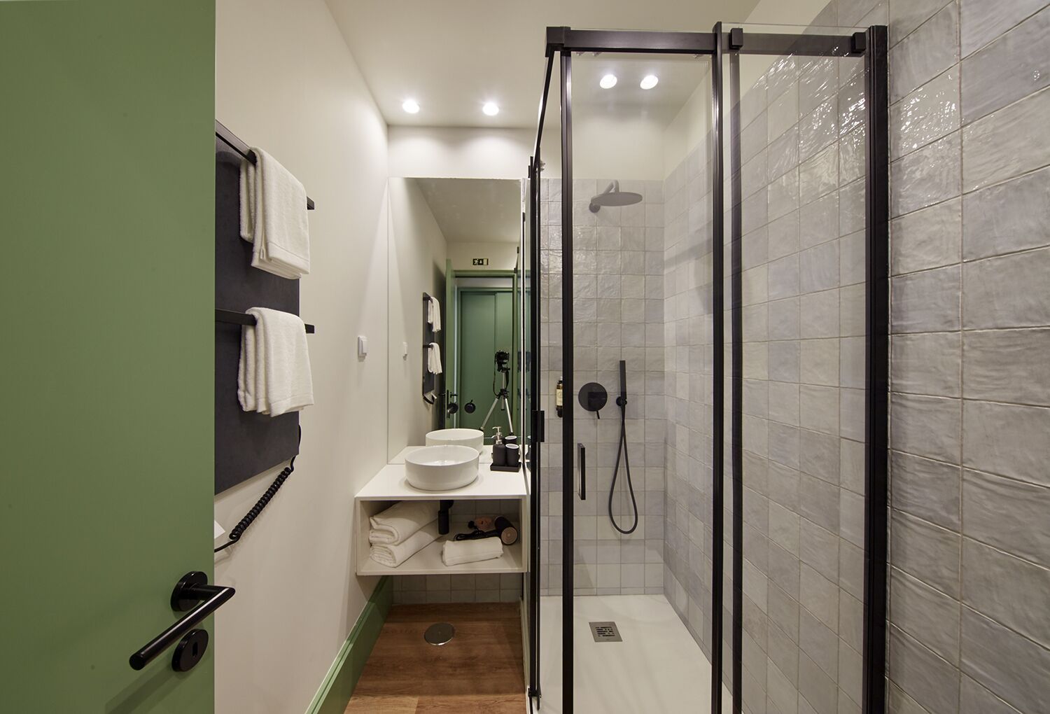 A compact bathroom with a glass-enclosed shower, a sink with a mirror, and a towel rack.