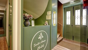A reception area with a green wall, a sign reading "Suntra Green Chalet," and a staircase leading to a door with a wrought iron design. - Sintra Green Chalet - Bed & Breakfast (Sintra)
