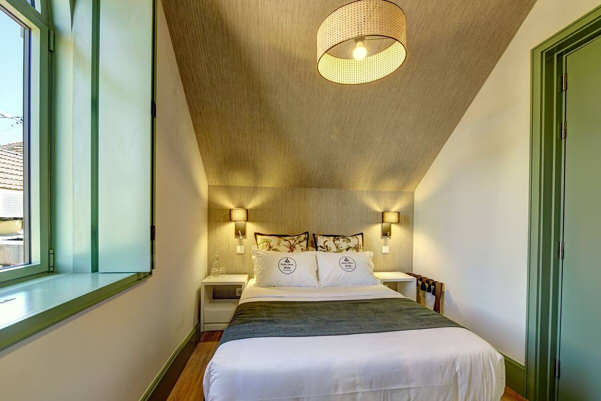 A bedroom with a bed, bedside tables, a window, and a ceiling light fixture.