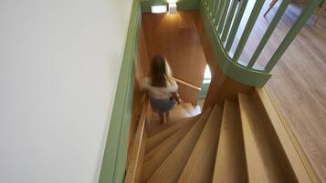 Una escalera de madera con barandal verde que lleva a una plataforma.