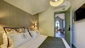 A hotel room with a bed, a wall-mounted TV, an air conditioning unit, and a door leading to another room. - Sintra Green Chalet - Bed & Breakfast (Sintra)