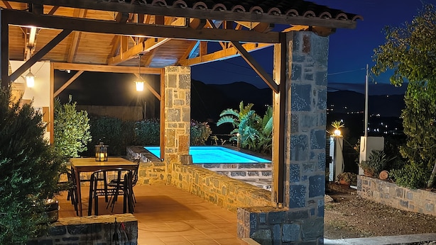 Un patio al aire libre con piscina, muros de piedra y una estructura de pérgola.