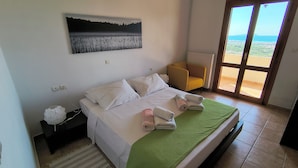 Un dormitorio con cama, una silla, un cuadro y vistas a través de una puerta.