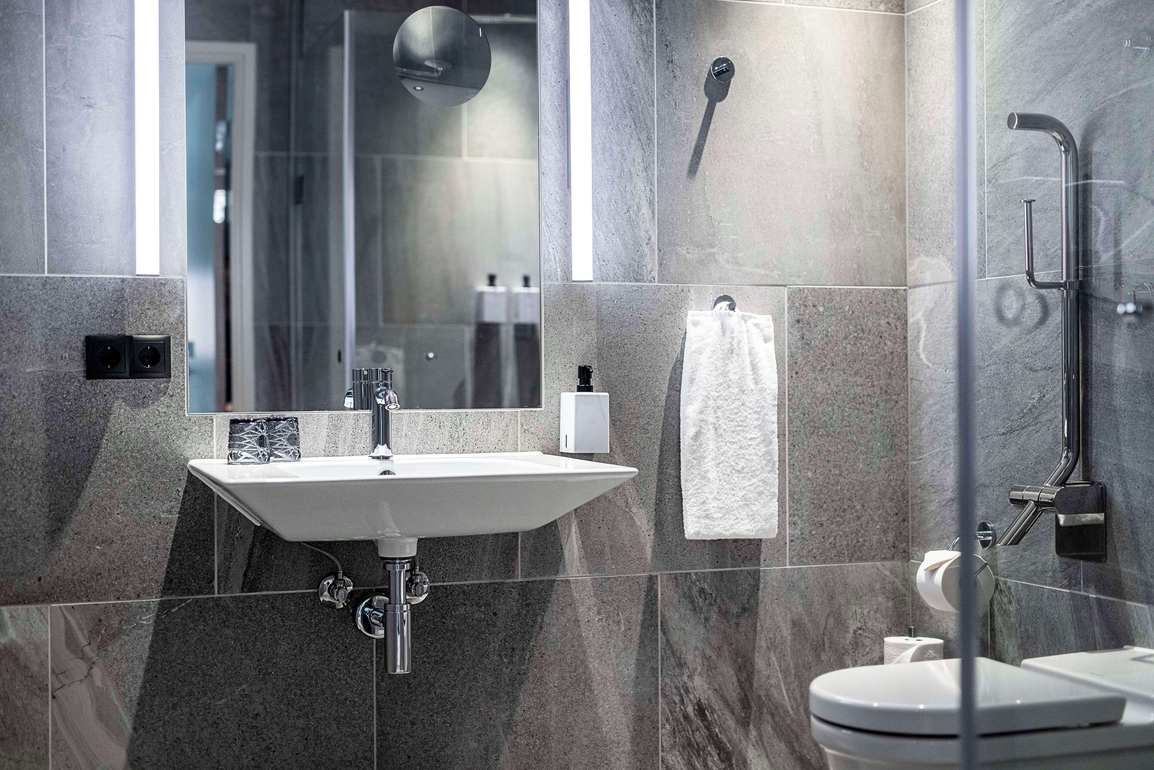 Ein modernes Badezimmer mit Waschbecken, Spiegel, Dusche und Toilette.