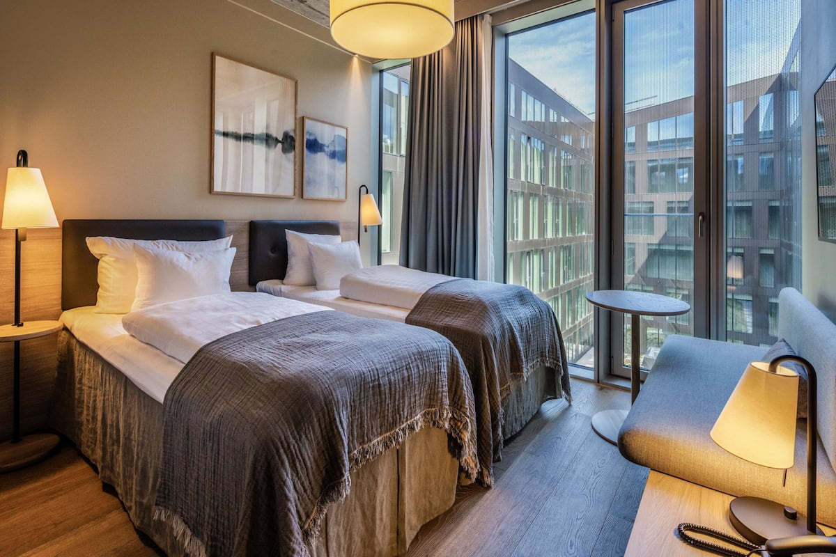 Une chambre d’hôtel avec deux lits, une petite table et un canapé.