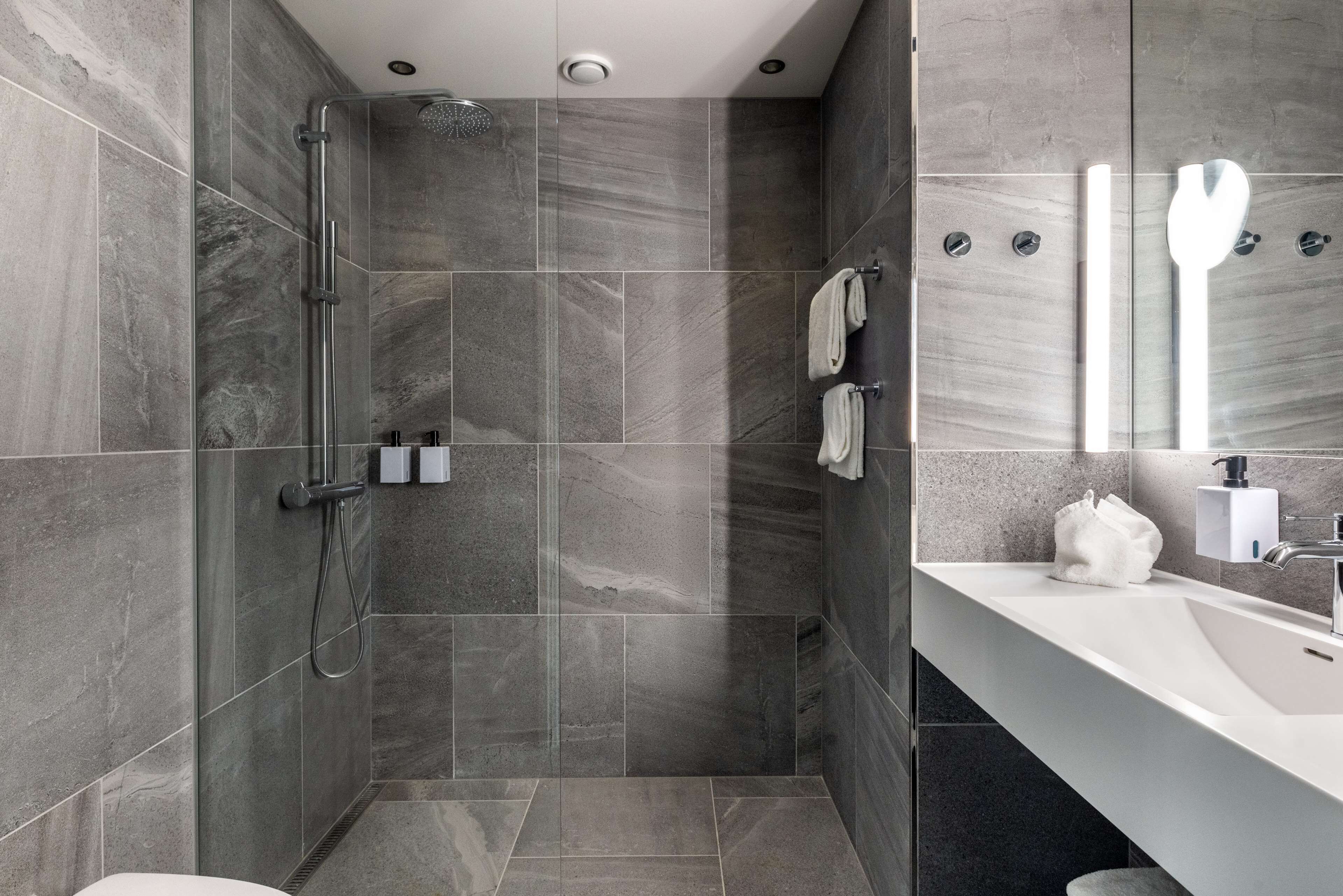 Een moderne badkamer met een douche, een wastafel en een spiegel.