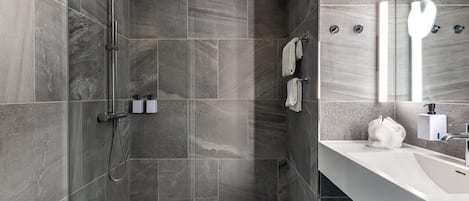 A modern bathroom with a shower, a sink, and a mirror.