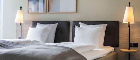 Una habitación de hotel con una cama grande, dos lámparas de noche y dos cuadros abstractos en la pared.