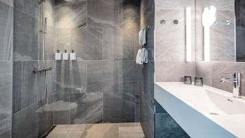 Un baño moderno con ducha de vidrio, lavamanos grande y azulejos de mármol.