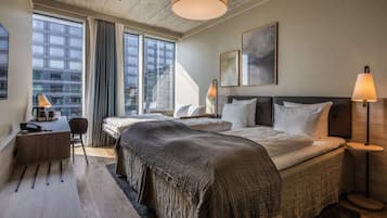 Een moderne hotelkamer met een groot bed, nachtlampjes, een bureau met stoel en uitzicht op de stad door grote ramen.