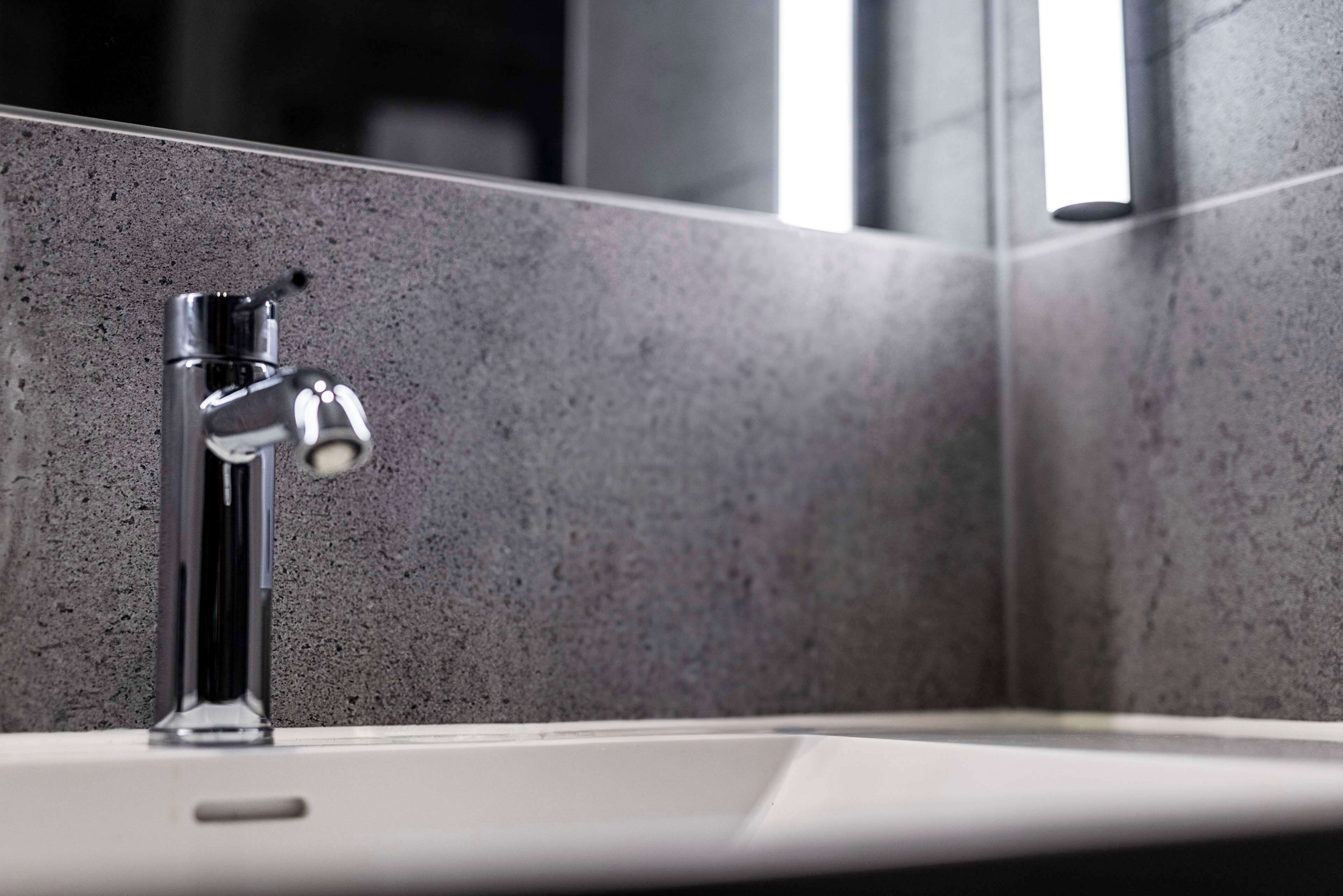 A modern bathroom with a chrome faucet and a white sink.