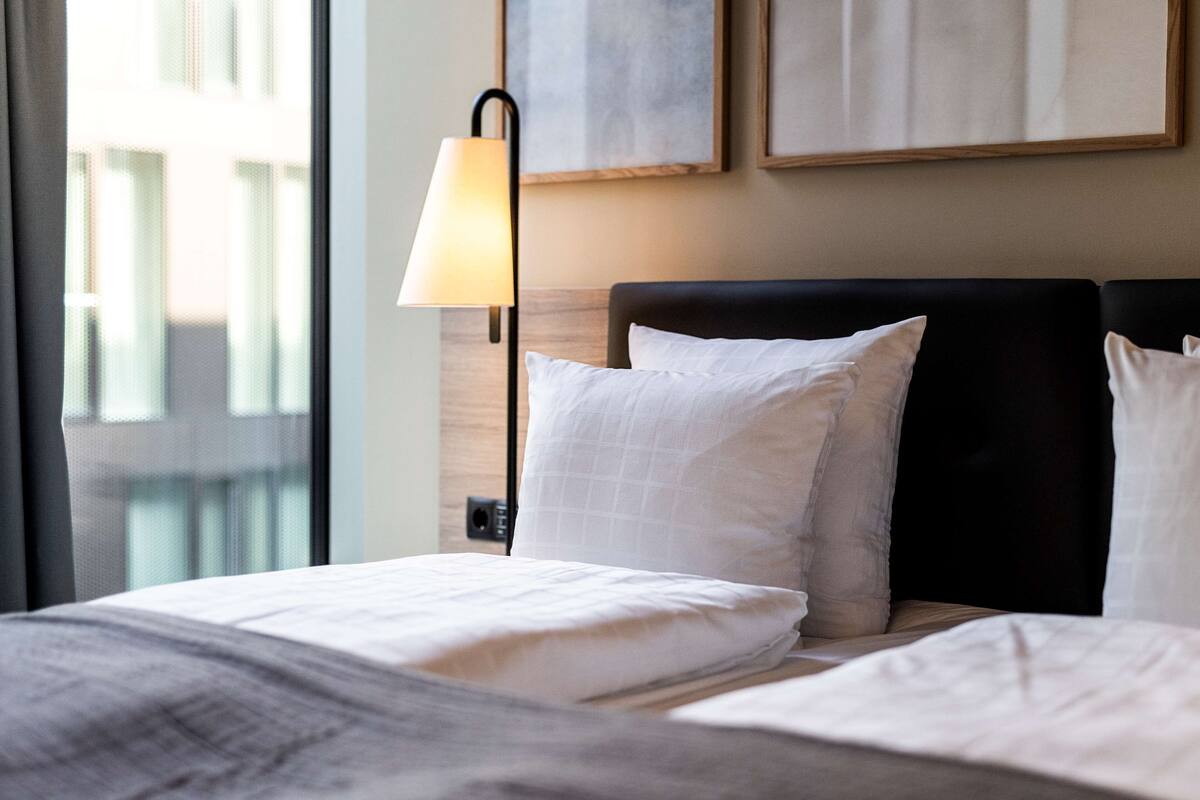 Une chambre d’hôtel avec un lit, une table de chevet, une lampe et des œuvres d’art accrochées au mur.