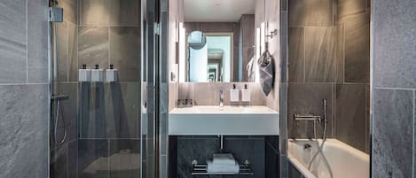 Un baño moderno con ducha envuelta en vidrio, un lavabo central y una bañera.