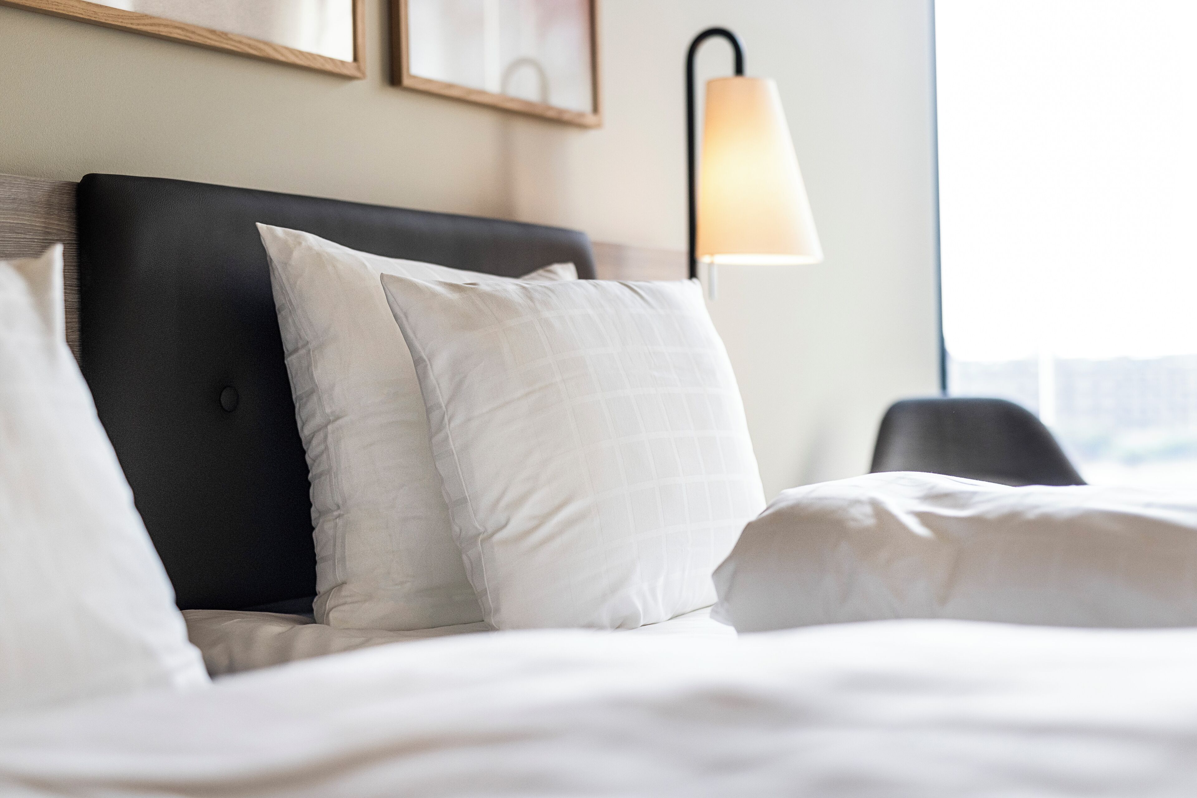 A neatly made bed with white bedding and a black headboard.