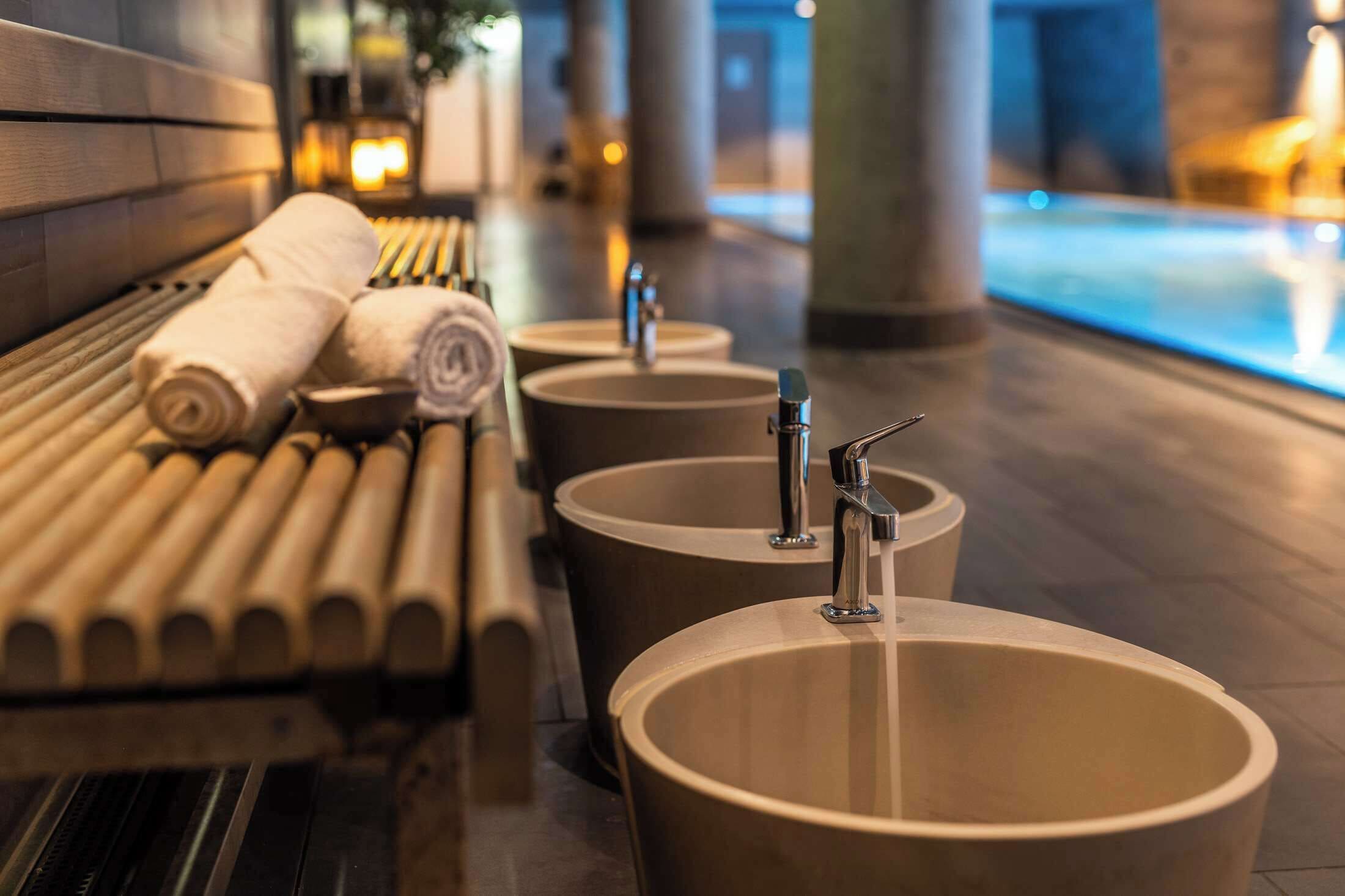 Un espace spa comprenant un banc et trois grands lavabos.