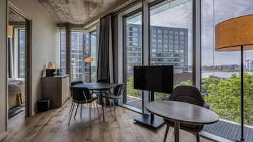 Una habitación moderna con un ventanal grande, un televisor de pantalla plana, una mesa de comedor y un sofá.