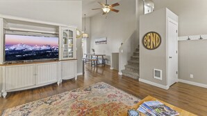 A living room with a television, a bookshelf, a staircase, and a 'BEND' sign on the wall. - Family Home | 2 King Suites + Fire Pit | Walk to Breweries (Bend)