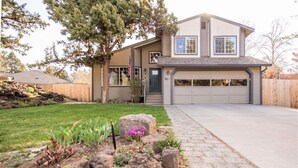 A two-story house with a garage, a well-maintained lawn, and a stone pathway leading to the entrance. - Family Home | 2 King Suites + Fire Pit | Walk to Breweries (Bend)