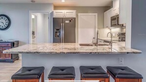 A modern kitchen with a marble countertop, stainless steel appliances, and a built-in oven. - 🏝️PET FRIENDLY 3-bedroom house, minutes from Beach,Heated Pool (Venice)