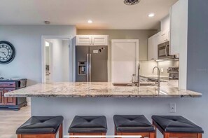A modern kitchen with a marble countertop, stainless steel appliances, and a built-in oven.