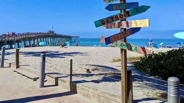 A beach with a wooden signpost with city names pointing in different directions. - 🏝️PET FRIENDLY 3-bedroom house, minutes from Beach,Heated Pool (Venice)