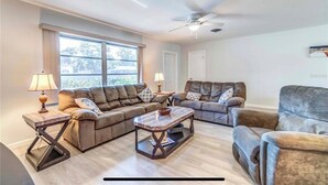 A living room with a sofa, two armchairs, a coffee table, and a ceiling fan. - 🏝️PET FRIENDLY 3-bedroom house, minutes from Beach,Heated Pool (Venice)