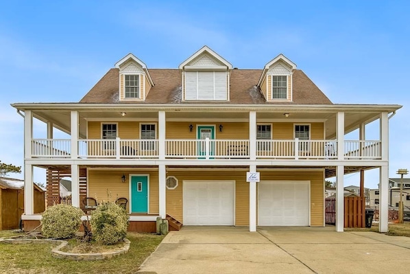 A two-story house with a front porch, two garages, and a small front yard.