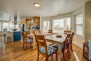 A spacious kitchen with wooden cabinetry, a central island, and a dining area with wooden chairs and a table.