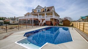 Una piscina condominiale con una casa sullo sfondo.
