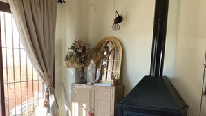 Un salon chaleureux avec une cheminée, un canapé, une table basse et un meuble contenant des objets décoratifs.