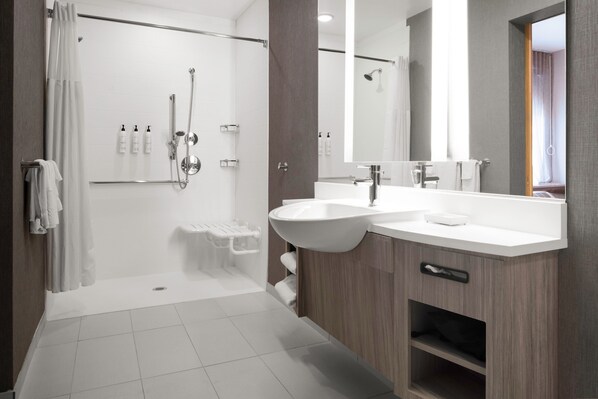 Un baño moderno con ducha a ras de suelo, tocador doble y un espejo grande.