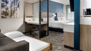 A hotel room with a bed, a desk, a chair, and a bathroom.