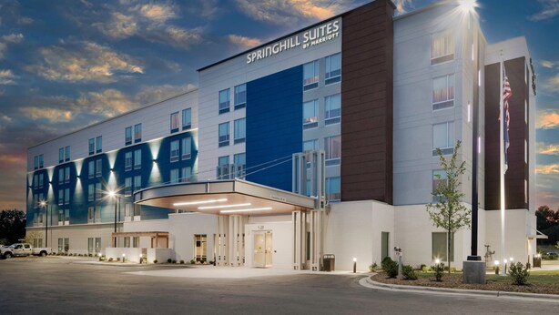 A modern hotel with a flat roof, multiple windows, and a prominent entrance.