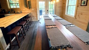 Un intérieur en bois avec un long bar, des tabourets et des tapis tissés sur le sol.