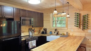 Une cuisine moderne avec des meubles en bois, des appareils électroménagers en acier inoxydable et un grand îlot central en bois, agrémenté de tabourets de bar.