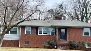 A single-story brick house with a front door, windows, and a small front yard. - Centrally Located Cozy House,2 king beds,Game Room (Greensboro)
