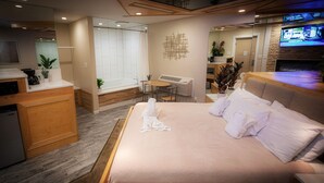 Ein Hotelzimmer mit Bett, Schreibtisch, Stuhl, Nachttisch und Fernseher.