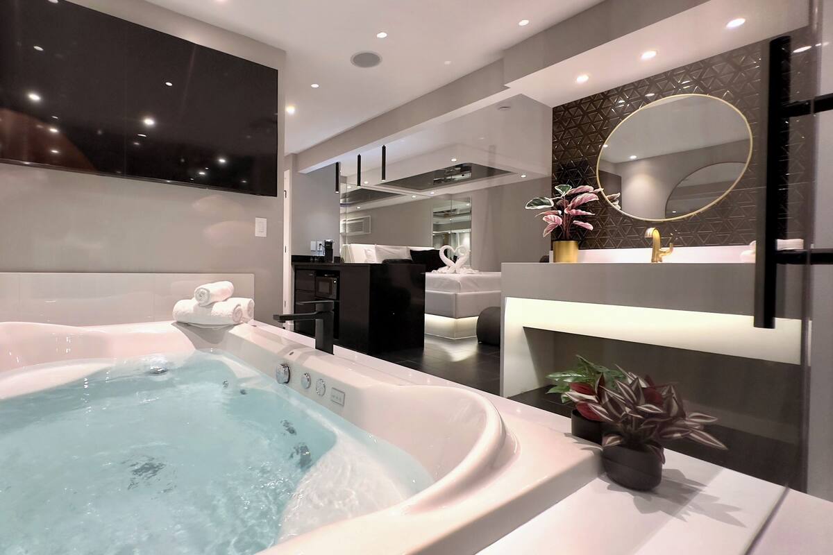 A modern bathroom with a large bathtub, a mirror, and a sink.