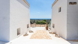 A pathway leading to a view of the sea, flanked by white buildings with a sign reading "Oltu & More Resort". - Villa Torre Dell'alto mare Blocco n.2 (Alliste)