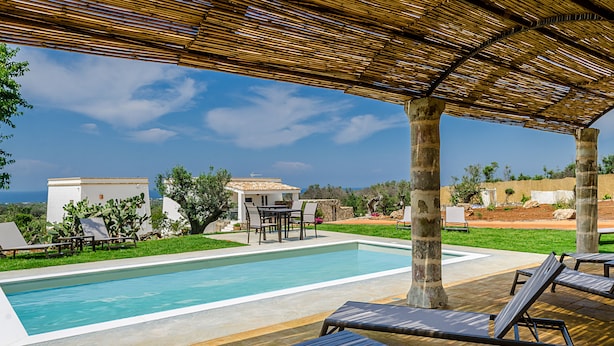 A pool area with lounge chairs and a table under a bamboo roof, surrounded by greenery and a view of the sea. - Villa Torre Dell'alto mare Blocco n.2 (Alliste)