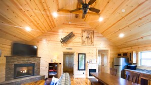 A cozy cabin interior with a fireplace, wooden floors, a dining area, and a kitchen. - 🪵 Murphy Cabin 🏔 Mountain View // 2Bed-2Bath // 6 guests // 10mins to town (Murphy)